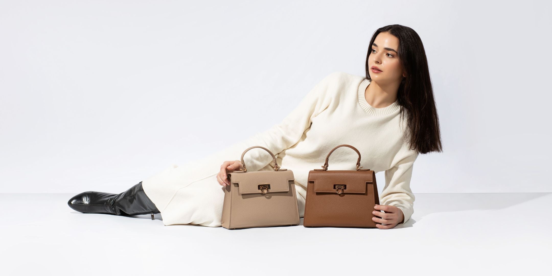 Model in white outfit hold two top handle bags in brown and taupe from layla collection by Levantine