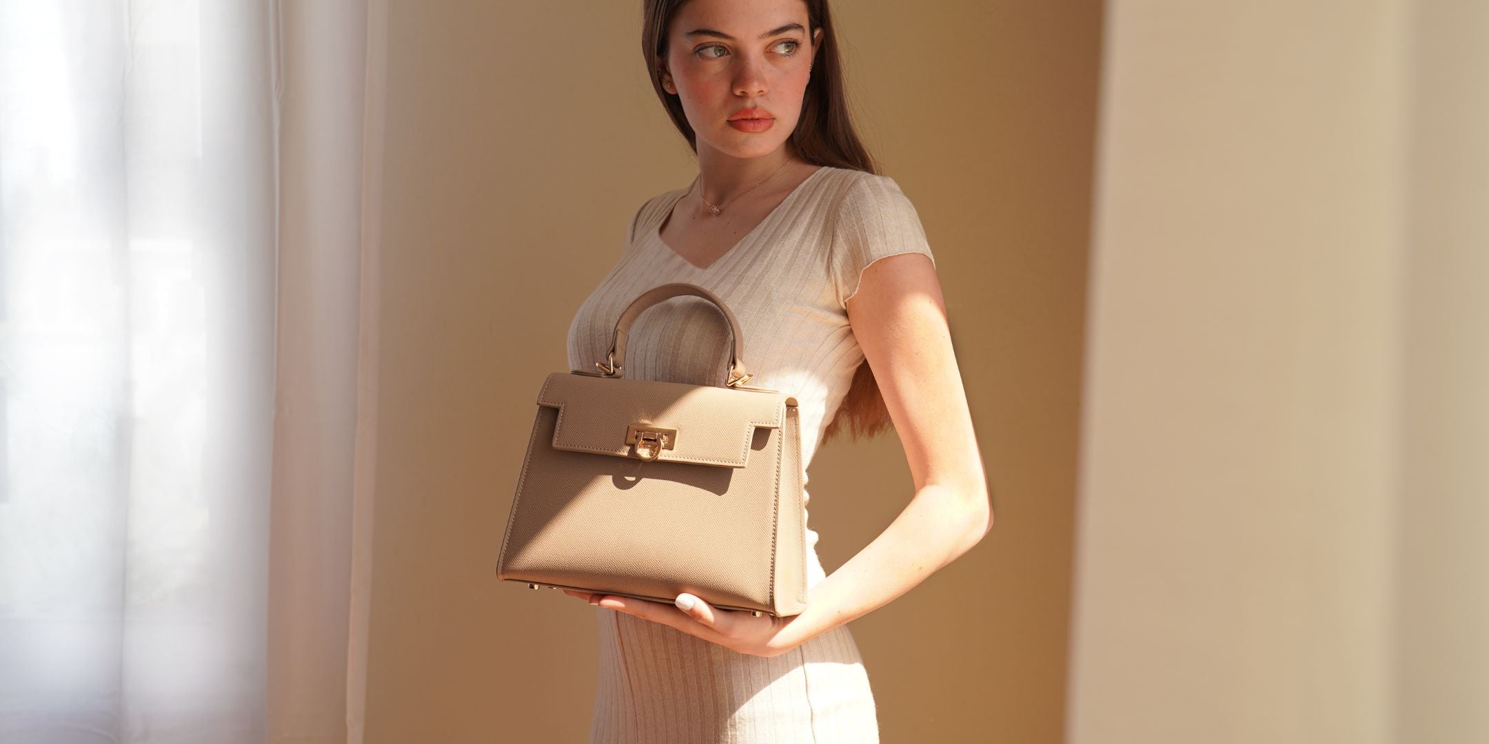 Fashionable woman showcasing a luxurious taupe handbag